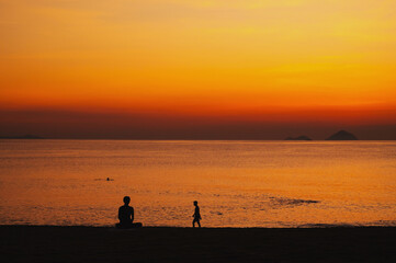 silhouettes on the beach by the sea in the morning at sunrise in summer