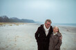 © Marko Geber - Elderly couple walking on a beach in winter coats