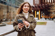 © maxbelchenko - Attractive woman in trench coat using phone outdoor in the street. Lifestyle, travel, tourism, technology