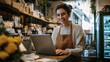 © EmmaStock - Happy small business entrepreneur working on a laptop in their store, managing their business with enthusiasm and joy