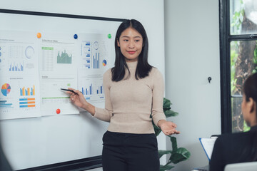 confident businesswoman presenting data: a young asian businesswoman confidently presents data and c