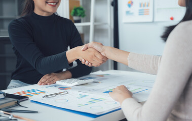 Businesswomen Handshake: Two professional women seal a deal with a firm handshake, symbolizing trust, collaboration, and a shared vision in a modern office setting.