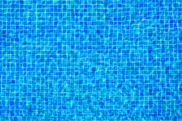 Rippled transparent water surface of swimming pool revealing view onto floor with small blue tiles