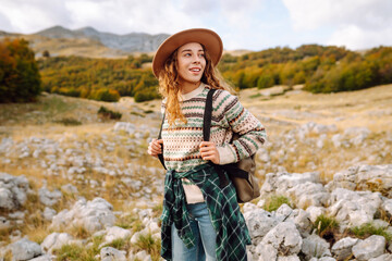 The female tourist carefully navigated the rocky terrain with her backpack full of supplies. Autumn landscape. Travel, nature concept