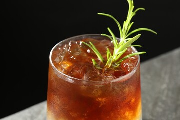 Refreshing espresso tonic drink with rosemary on dark background, closeup