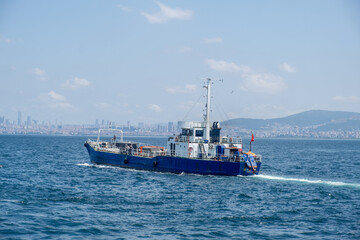 Poster - A blue cargo boat navigates through clear waters near Istanbul under a bright sky