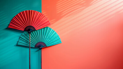 Poster - Two large decorative fans in red and teal are displayed on a striking wall divided into complementary colors, creating an artistic and vibrant atmosphere for interior design. Copy space