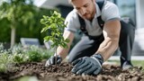 A dedicated gardener crouches to plant a vibrant young tree in fresh soil, showcasing the hopeful essence of growth, nature, and nurturing amidst a verdant backdrop.