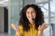 © Liubomir - Friendly hispanic businesswoman in office wearing headset during video call looking at camera. Perfect image for customer service, telecommuting, or video conferencing concepts.