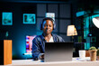 © DC Studio - Relaxed black woman listens to music while typing on her laptop at her home workstation. African american female entrepreneur with wireless headset and minicomputer, utilizing modern technology.