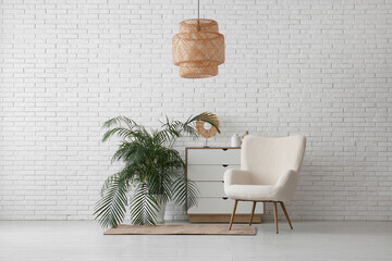 Canvas Print - Cozy armchair, chest of drawers and houseplant near white brick wall