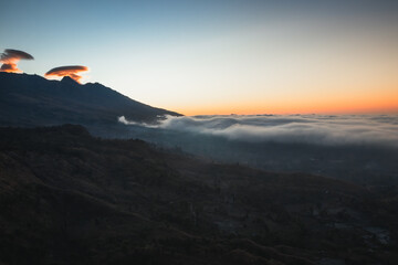 A sheet of cloud engulfing a mountain valley at sunset.