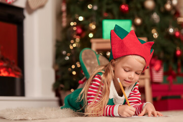 Canvas Print - Cute little girl in elf costume writing letter to Santa at home on Christmas eve