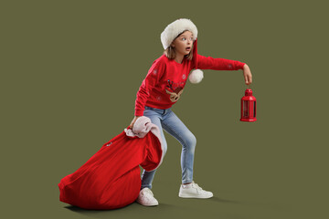 Poster - Cute shocked girl in Santa hat with bag and lantern on green background