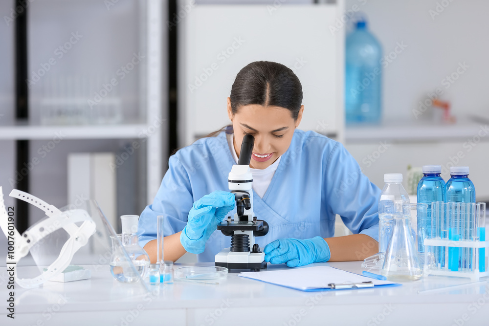 Happy female young scientist with microscope examining water quality in research laboratory
