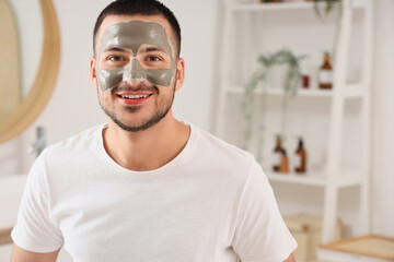 Poster - Handsome young happy man with cosmetic clay mask on face in bathroom at home