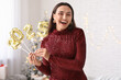 © Pixel-Shot - Happy young woman with figure 2025 made of foil balloons in living room. Christmas celebration