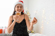 © Pixel-Shot - Beautiful young woman in Santa hat with Christmas sparkler and glass of champagne in living room