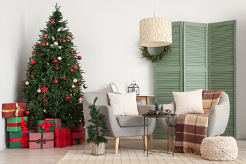 Interior of festive living room with grey armchairs, Christmas tree and gift boxes