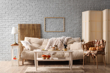 Poster - Interior of modern living room with autumn decor, sofa and armchair