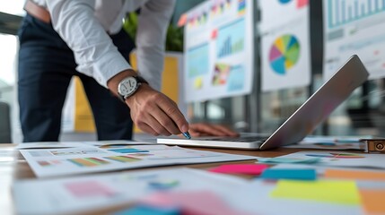 Poster - Businessman analyzing data and charts on a laptop at his desk in an office.