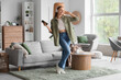 © Pixel-Shot - Young woman in headphones with mobile phone dancing at home