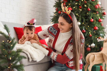 Poster - Happy mother with her little baby in Santa hat at home on Christmas eve