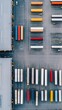© Kitta Studio - Aerial view of a busy freight yard with colorful shipping containers and trucks organized in neat rows, showcasing logistics operations.