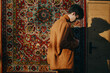 © SHOTPRIME STUDIO - Young man in a brown jacket standing against a colorful patterned rug, showcasing a thoughtful pose and soft lighting