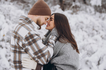 A young happy and loving couple walking in a winter snowy forest in the mountains