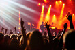 © oksa_studio - concert scene with excited fans raising their hands, illuminated by dynamic stage lights.