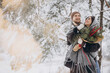 © anatoliycherkas - Cute young couple in love with pine bouquet spending time on Valentine's day in snowy winter forest in mountains
