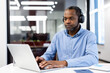 © Liubomir - Professional man wearing headphones works intently on laptop in modern office. Demonstrates focus and productivity. Captures essence of technology use and business communications in workplace.
