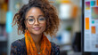 © danielkosh - Young professional woman with glasses and an orange scarf is smiling in a modern office