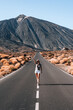 © Nestor - Woman walks along a deserted road with a mountain Teide background