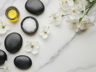 Spa setup with stones, salt, oil, and flowers on a marble background.