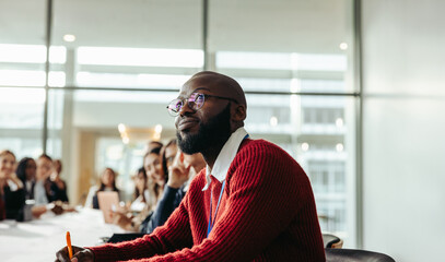 Wall Mural - African American businessman attentively listening during a group conference in a modern office setting