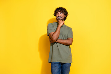 Wall Mural - Photo of clever guy with stylish wavy hair dressed khaki t-shirt palm on chin look at logo empty space isolated on yellow color background