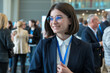 © PixelMocks - Confident Young Woman Engaging at a Business Conference