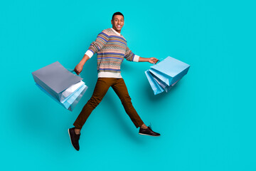 Wall Mural - Full body portrait of nice young man shop bags jump wear pullover isolated on turquoise color background