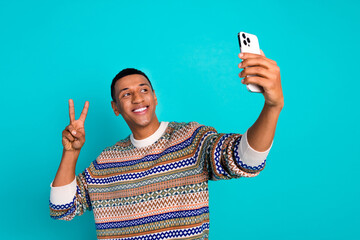 Wall Mural - Portrait of nice young man phone make selfie v-sign wear pullover isolated on turquoise color background