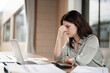 © wichayada - Stressed Business Woman Working at Desk with Laptop and Documents in Modern Office Environment