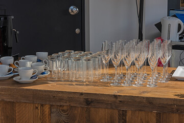 champagne glasses, drinking glasses and cups and saucers stand on a wooden bar