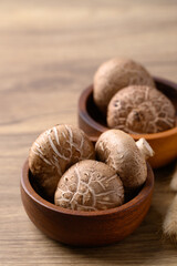 Wall Mural - Fresh shiitake mushroom in bowl on wooden background, edible mushroom and food ingredient in Asian cuisine