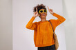 © David - Portrait of stylish Happy african american woman in afro hair standing carrying shoulder bag with sunglasses and making hand posing on white background