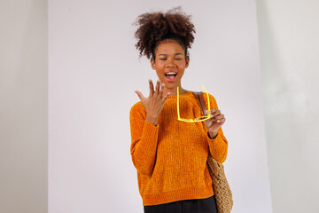 Portrait of stylish Happy african american woman in afro hair standing carrying shoulder bag with sunglasses and making hand posing on white background