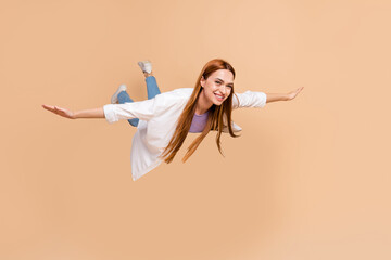 Poster - Full size photo of optimistic woman wear white cardigan flying in empty space hold hands like wings isolated on beige color background