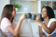 © PheelingsMedia - Happy interracial roommates toasting talking at home
