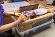 © Tosh Lubek - Moving Day: Packing clothes into plastic storage bins on living room floor ready for back to college