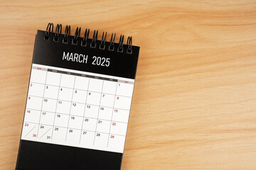 March desk calendar for 2025 year on wooden floor.